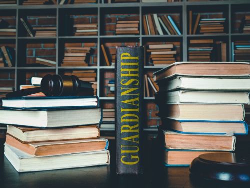 Book titled guardianship on desk with stacks of other books and a judge's gavel - Legal guardianship concept