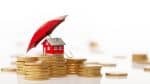 Red toy house is sitting behind a coin stack under a red umbrella. - Ohio estate planning strategies to protect your assets concept